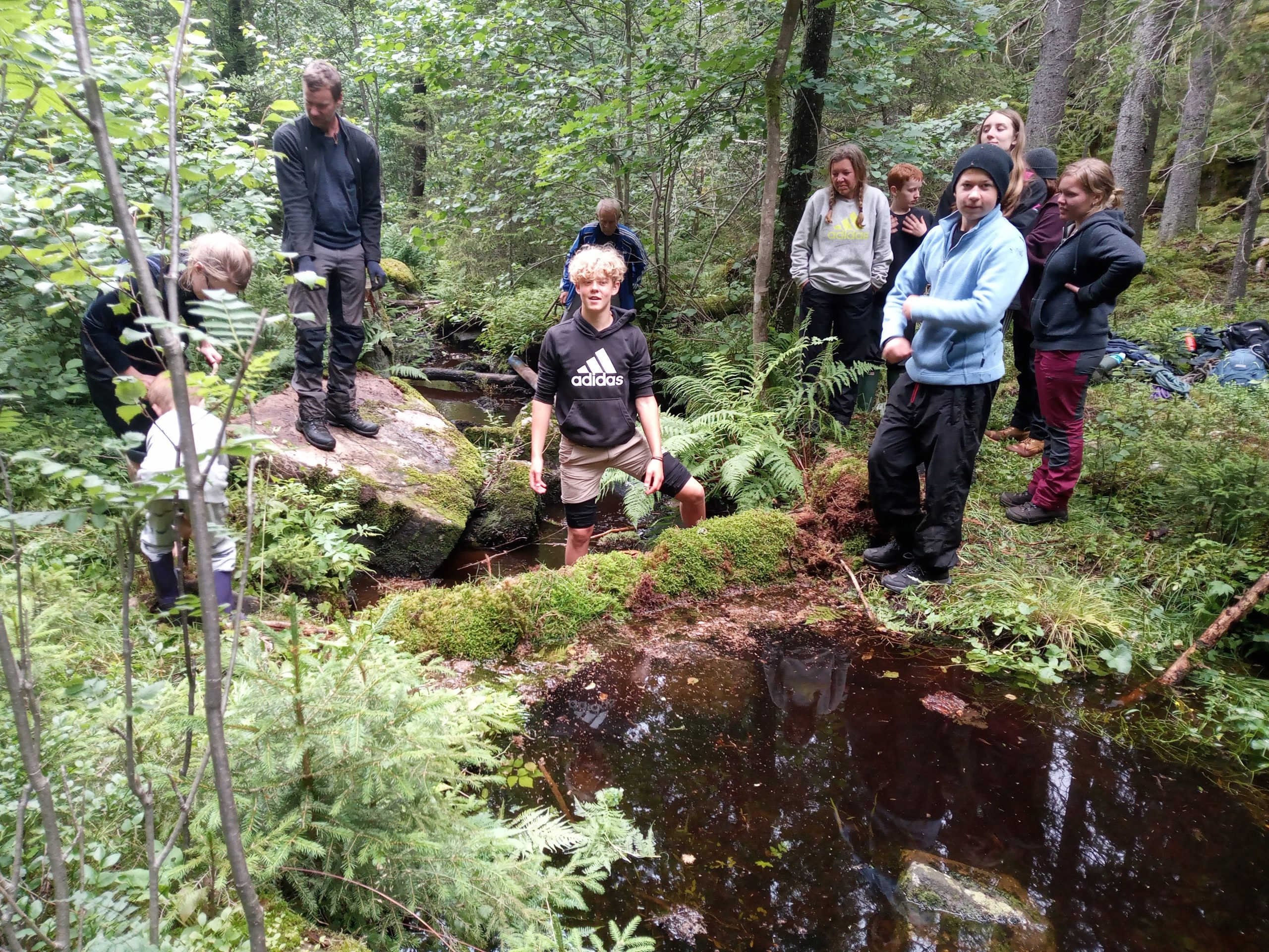 Ett gäng barn står med händerna uppsträckta och tittar mot solnedgången. De ser ut som svarta silhuetter mot den blå och gula himlen.